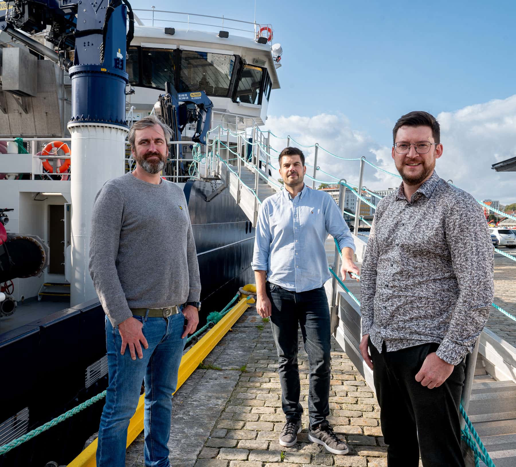 Nortech AI founders Anders, Francisco and Halvard beside a vessel at the dock.